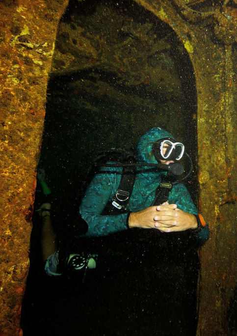 Un buzo dentro del naufragio del C-55 en Cancún, vistiendo un traje de neopreno de camuflaje.