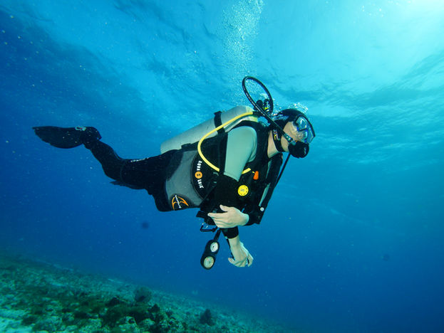 Un buceador en un viaje de buceo en Cancún, México en un fondo marino azul celeste