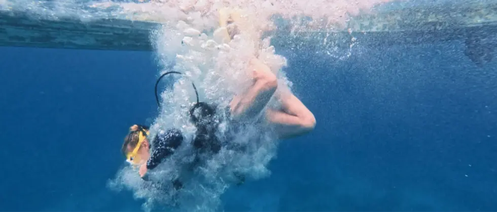 Scuba diver girl getting into the ocean