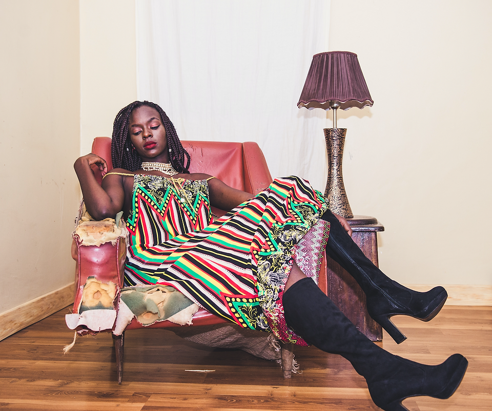 A woman of colour sitting in armchair, wearing stripy dress