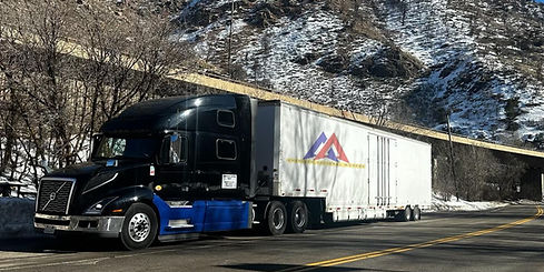 A photo of an American National Movers truck logo by mountains parked near a high-way.