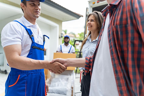 male long distance mover in blue uniform shaking happy customers hand after a fast delivery.
