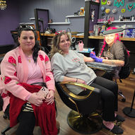 Two women smiling, one receiving a tattoo by Annie Pajamie