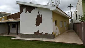 Casa com pintura descascada amarela e marrom, precisando de reforma.