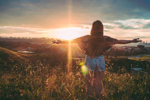 A woman spreading her arms during sunrise