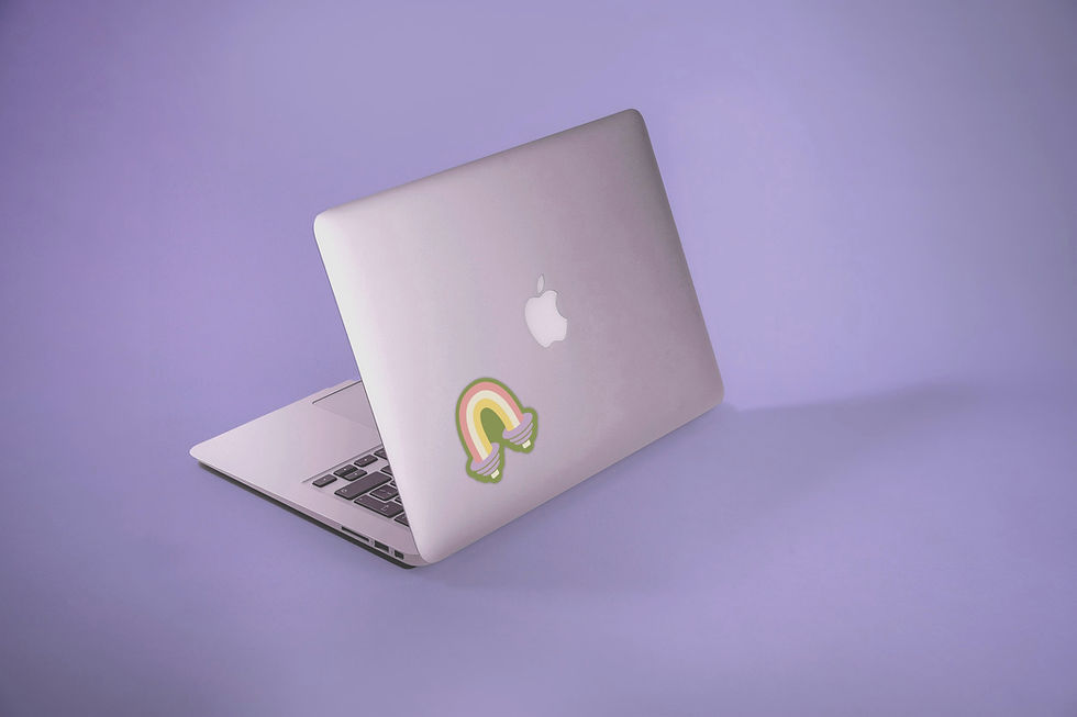 Geöffneter Laptop mit Regenbogen-Sticker auf der Rückseite vor lila Hintergrund.