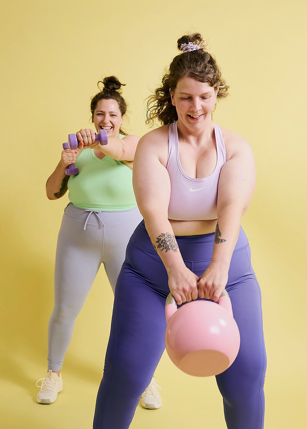 Zwei Frauen in Sportkleidung heben Hanteln an und strahlen dabei Fitness und Selbstbewusstsein aus.
