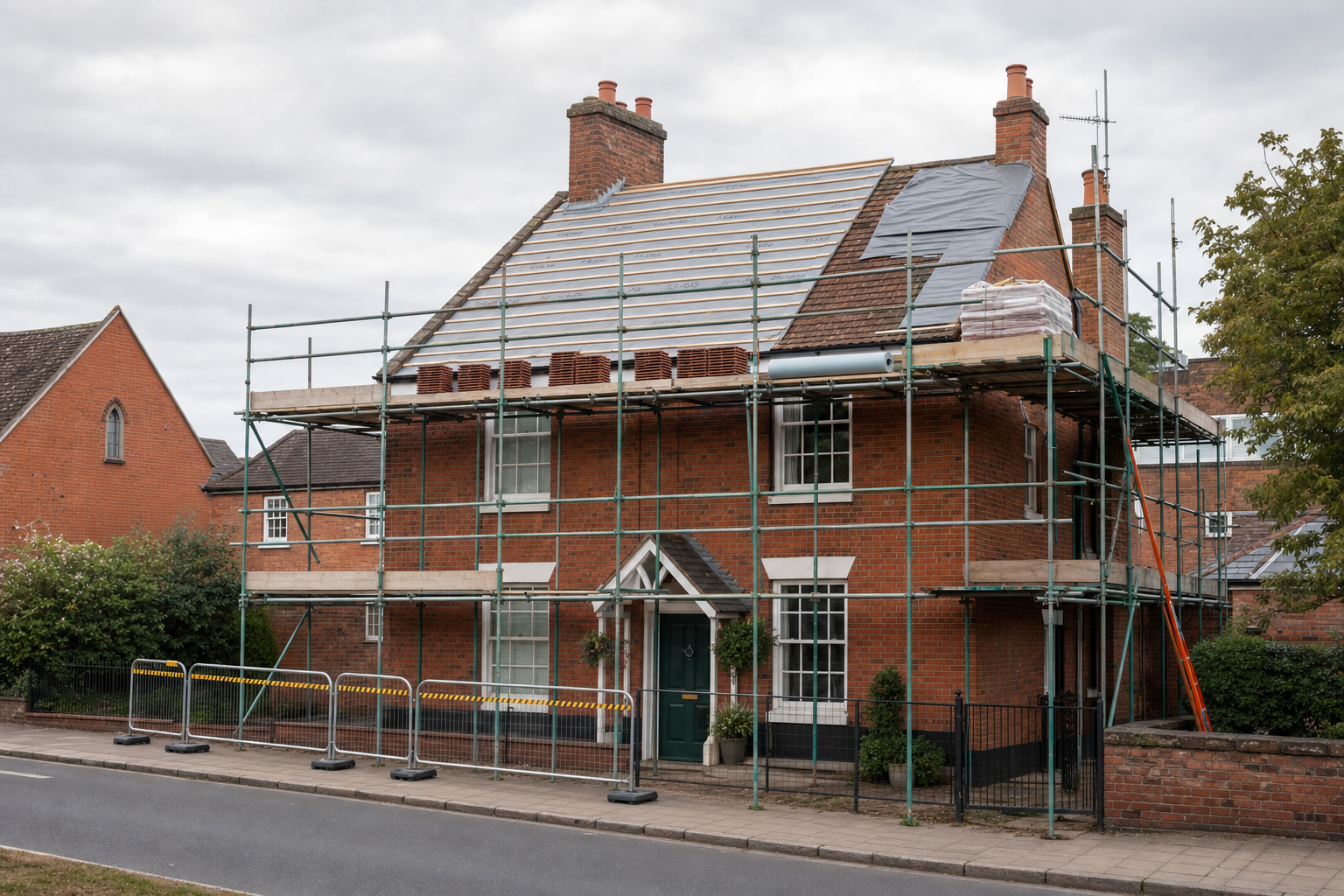 Scaffolding surrounds a red brick house under roof renovation on a cloudy day.