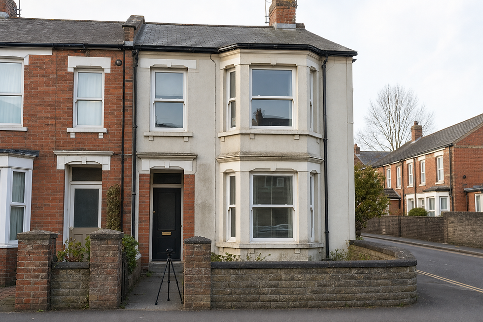 A terrace house with a bay window and a camera tripod on the pavement in front.