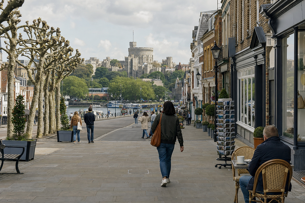 People strolling along a tree-lined street with Windsor Castle in the background on a cloudy day.