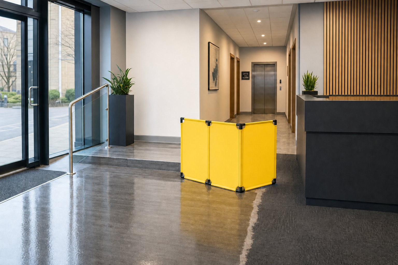 Yellow safety barrier placed on a partially cleaned floor in a modern office lobby near the elevator.