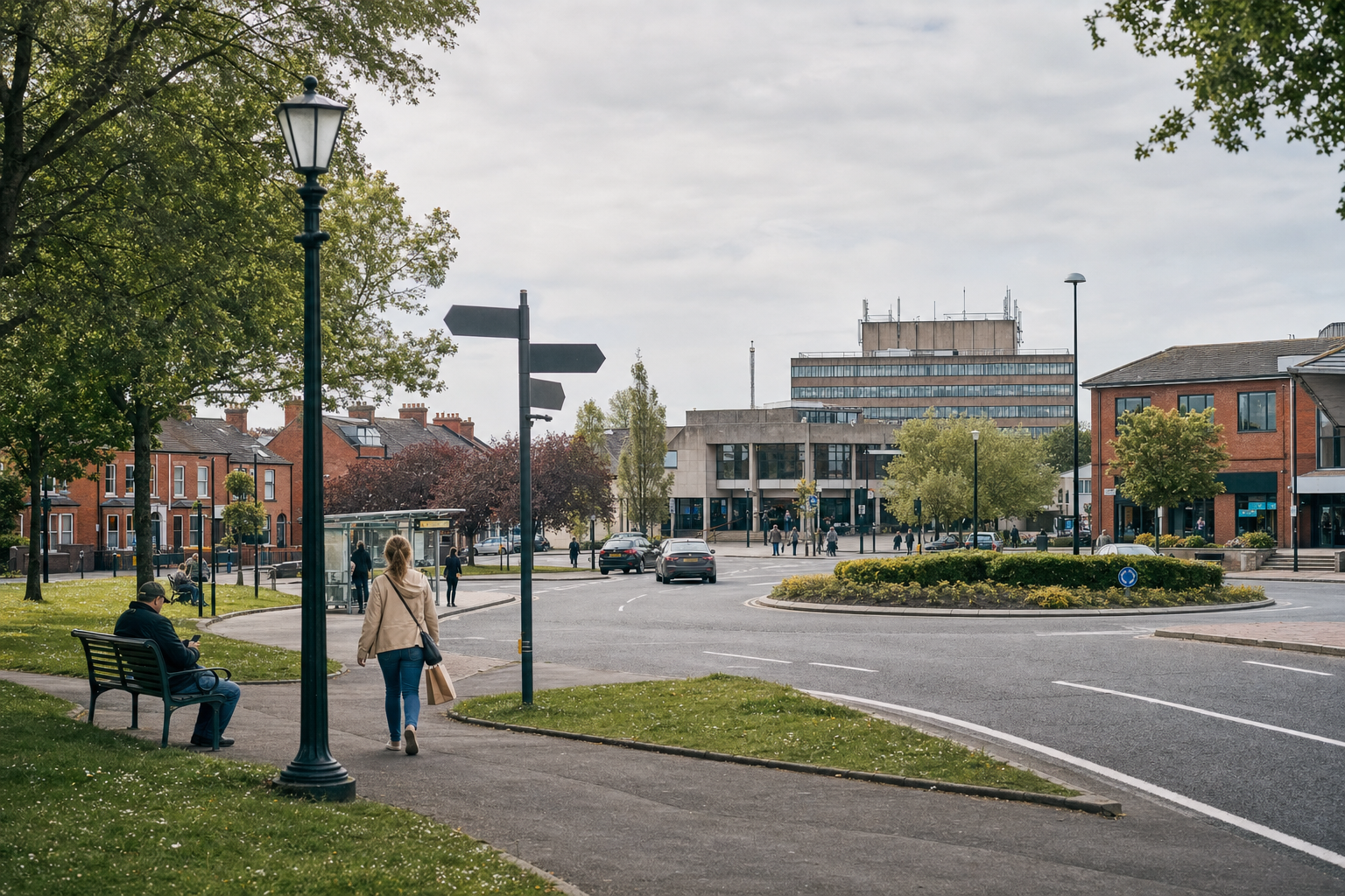 A woman walks towards a town centre with modern and historic buildings, surrounded by greenery and a roundabout.