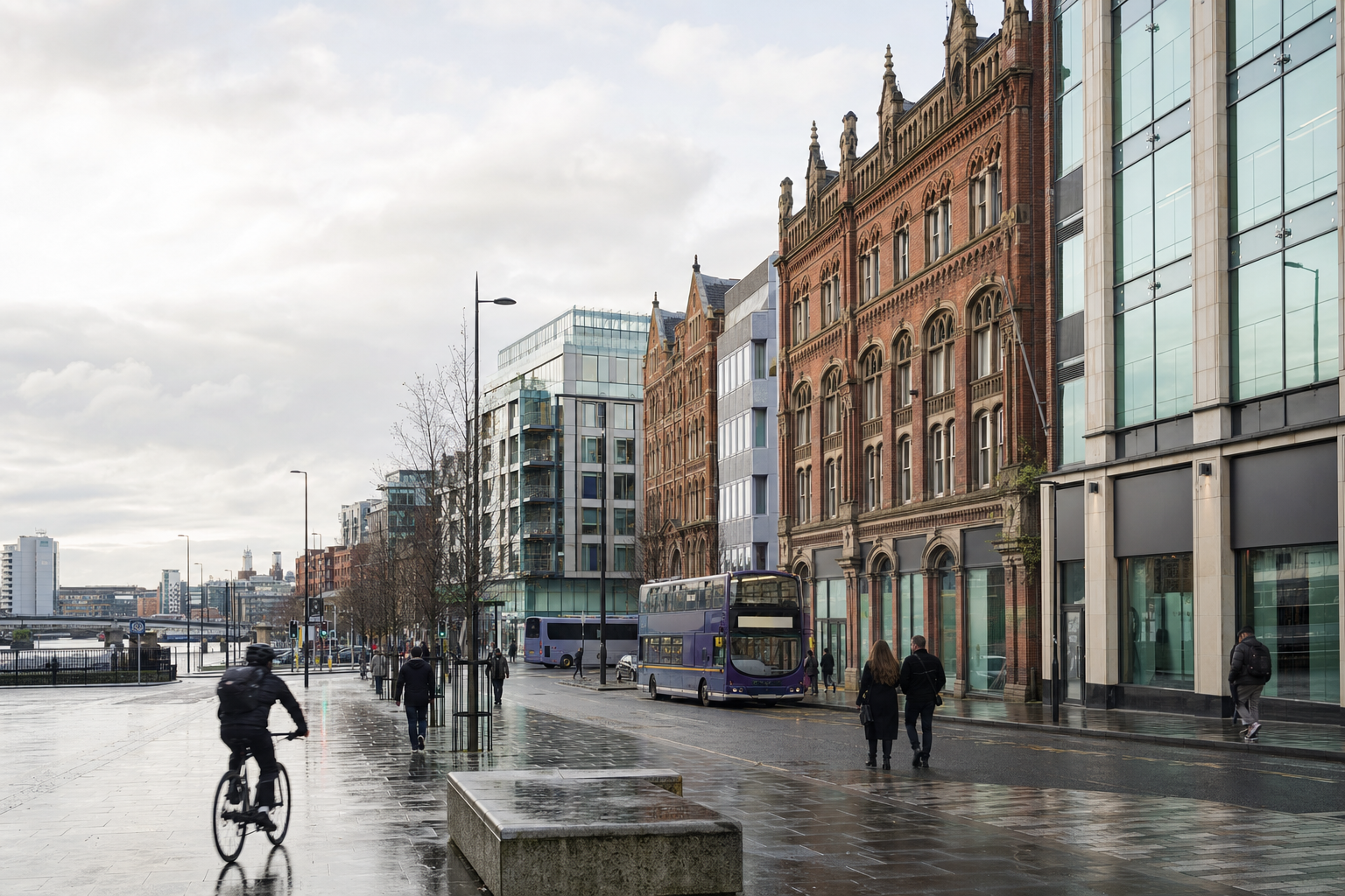 Cyclist and pedestrians on a wet city street lined with historic and modern buildings.