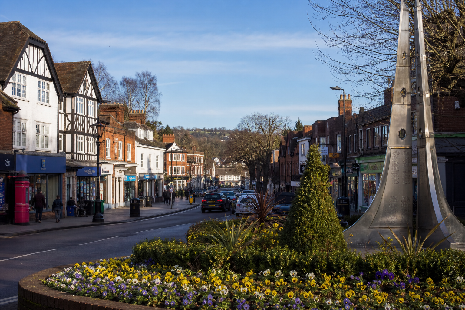 A busy street in a quaint town with half-timbered buildings and a colorful flower bed.