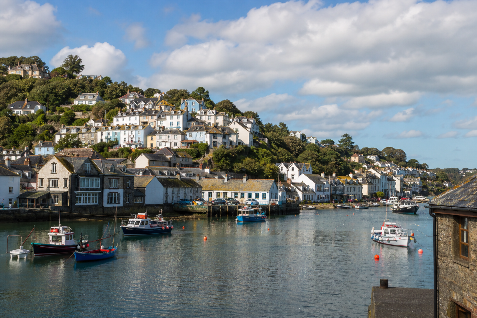 Charming coastal town with colorful hillside houses overlooking a serene harbor with small boats.