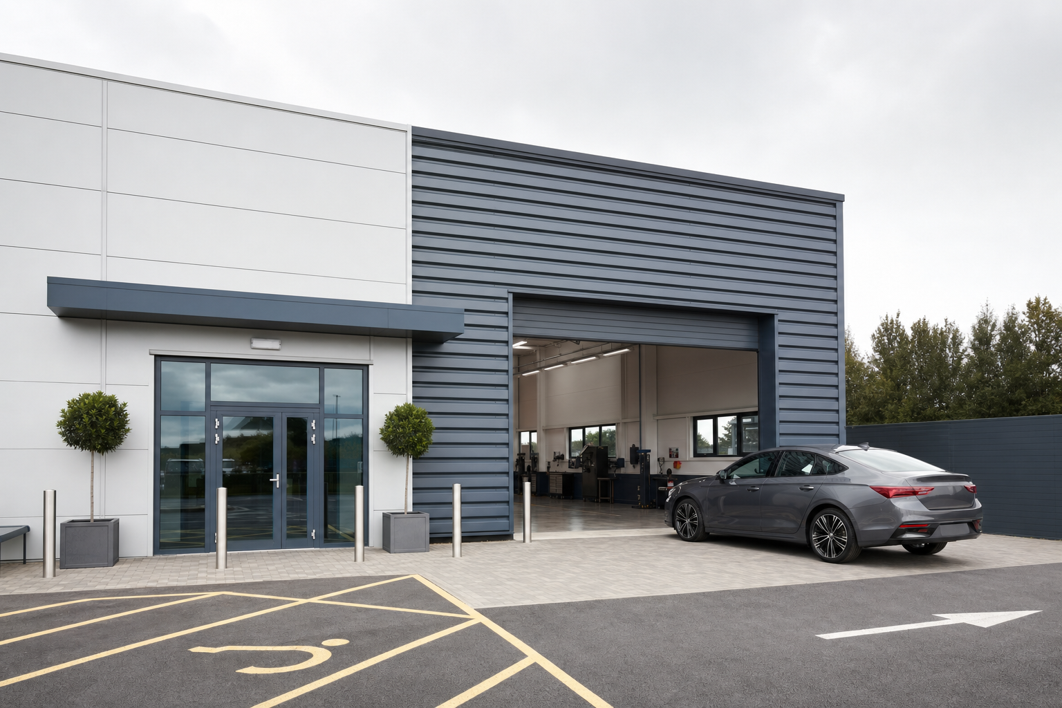 A modern industrial building with a sleek grey car parked near the open garage, next to a marked accessible parking space.