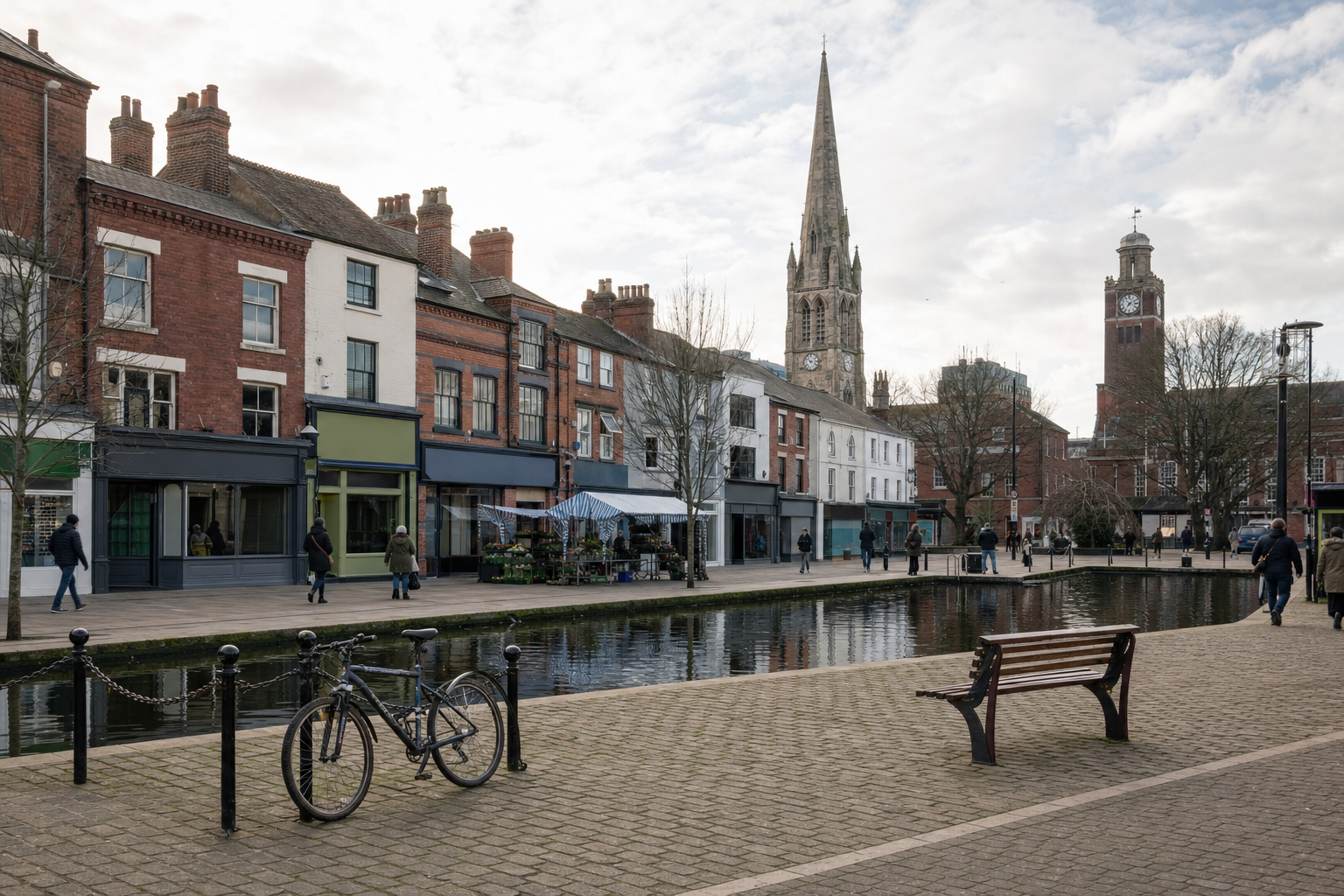 A bicycle is parked by a canal in front of historic buildings with church spires in the background.