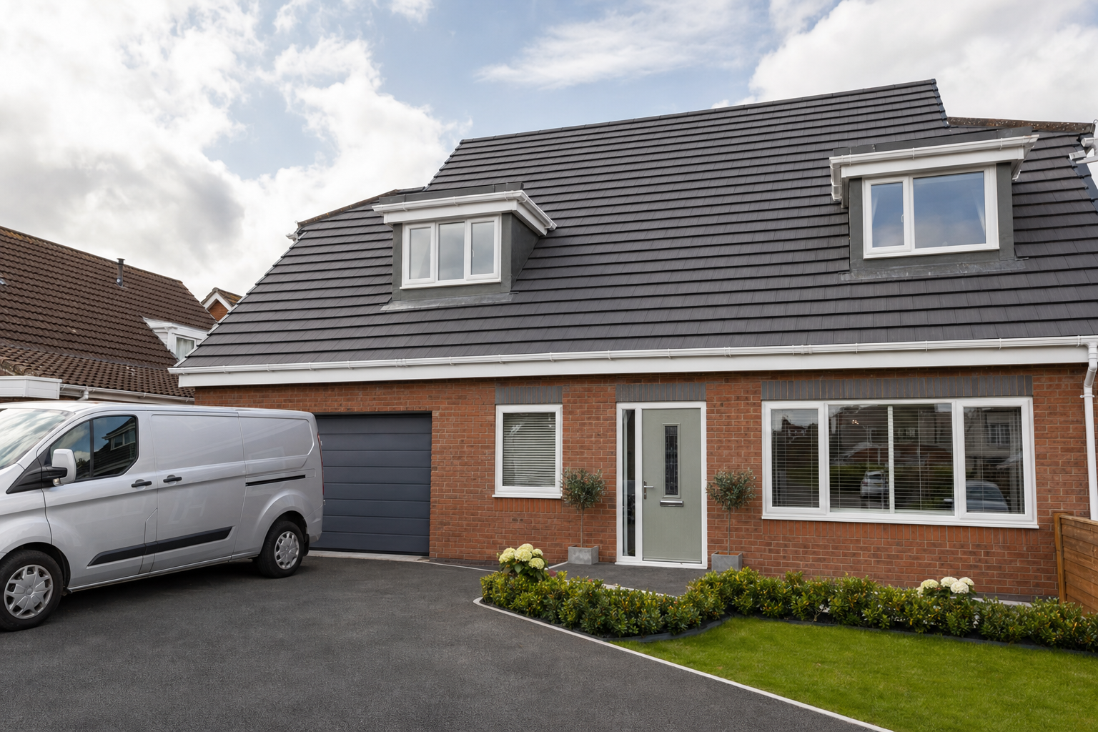 Modern brick house with grey tiled roof, a white van parked in the driveway, and well-maintained garden in front.