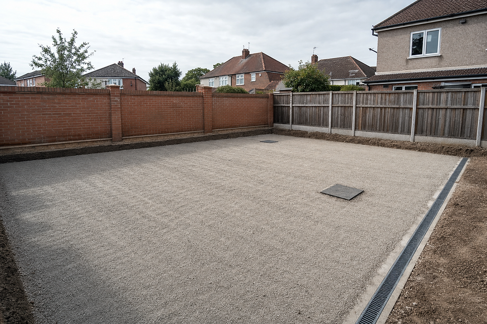 A levelled gravel area bordered by red brick and wooden fences in a residential garden setting.