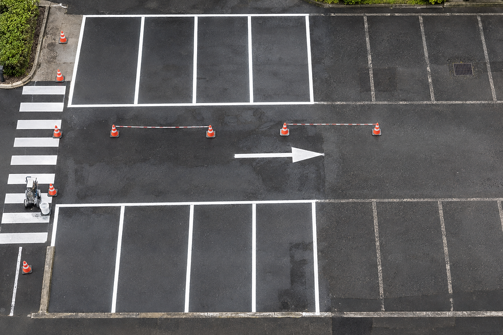 Empty car park with freshly painted white lines, traffic cones, and a white arrow pointing right.