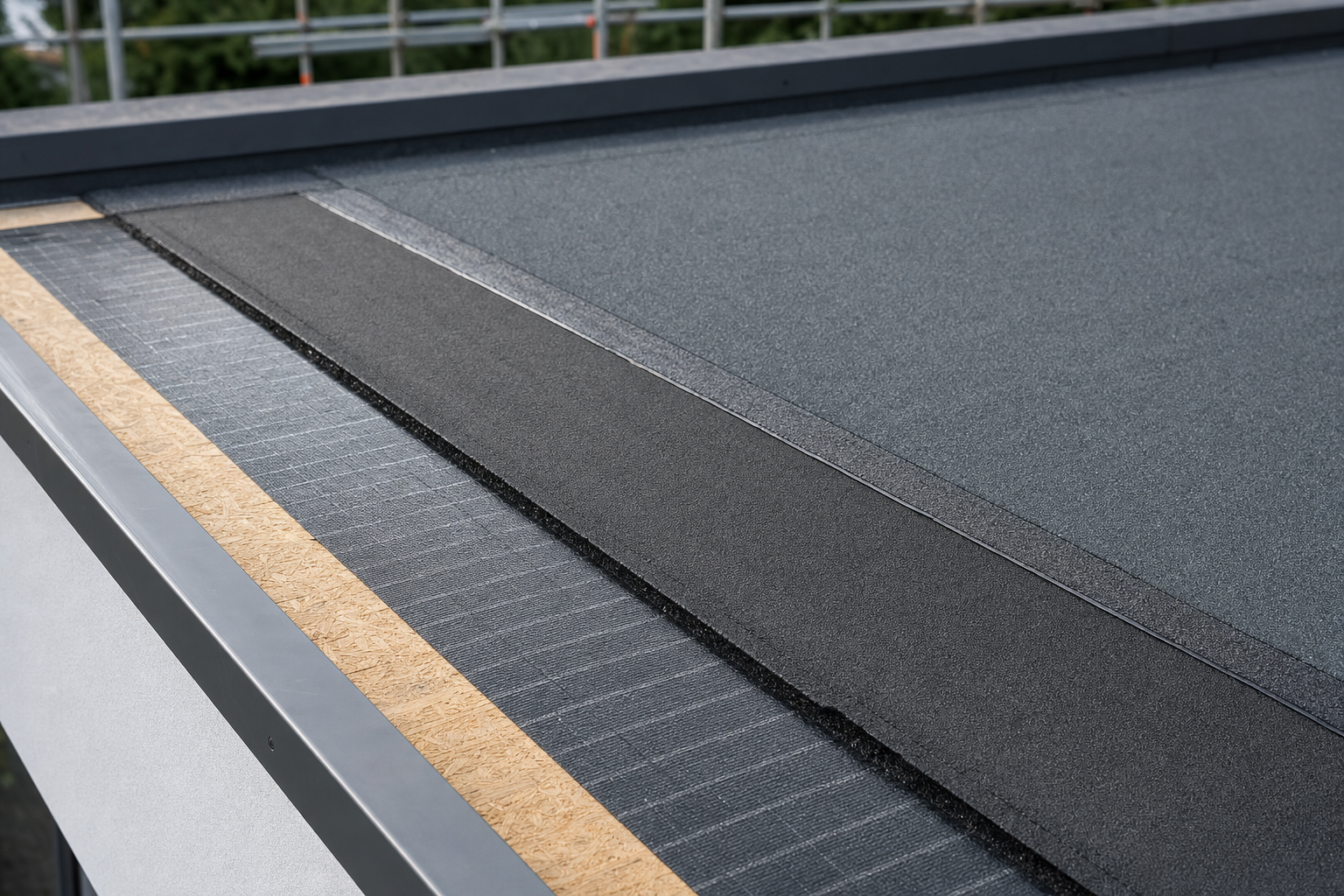 Close-up of a flat roof installation showing multiple layers of roofing materials.