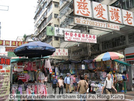 Bustling street market with signs and shoppers.