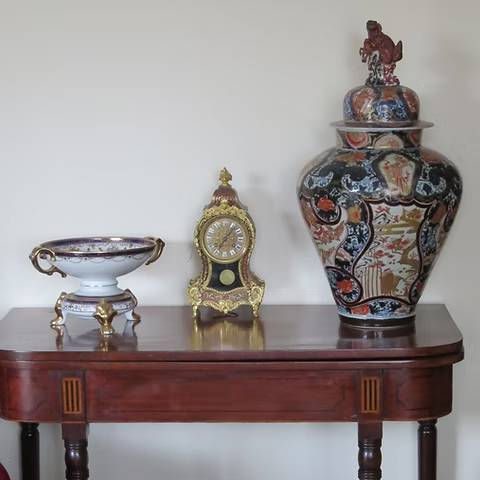 Antique mahogany table with decorative porcelain bowl ornate brass mantel clock and large lidded oriental vase