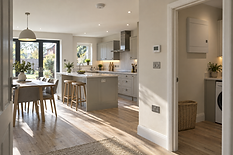 Modern kitchen and dining area with grey cabinets, wooden flooring, and large glass doors opening to a garden.