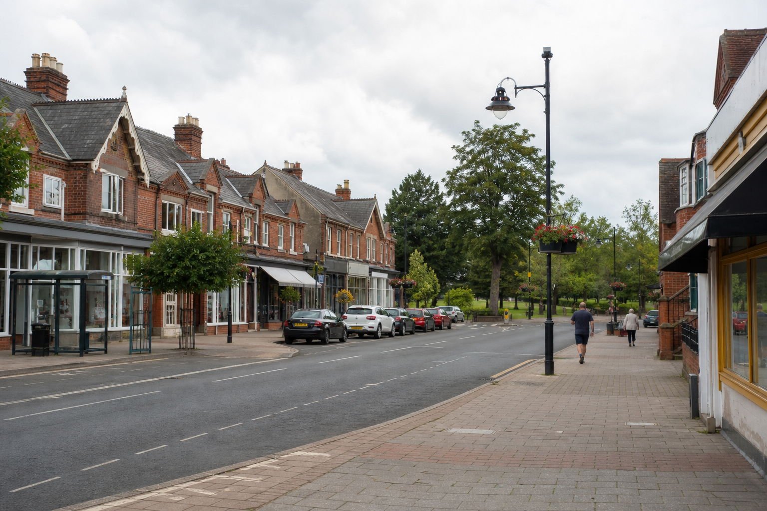 A quiet street with red-brick buildings, parked cars, and pedestrians, framed by trees and a cloudy sky.
