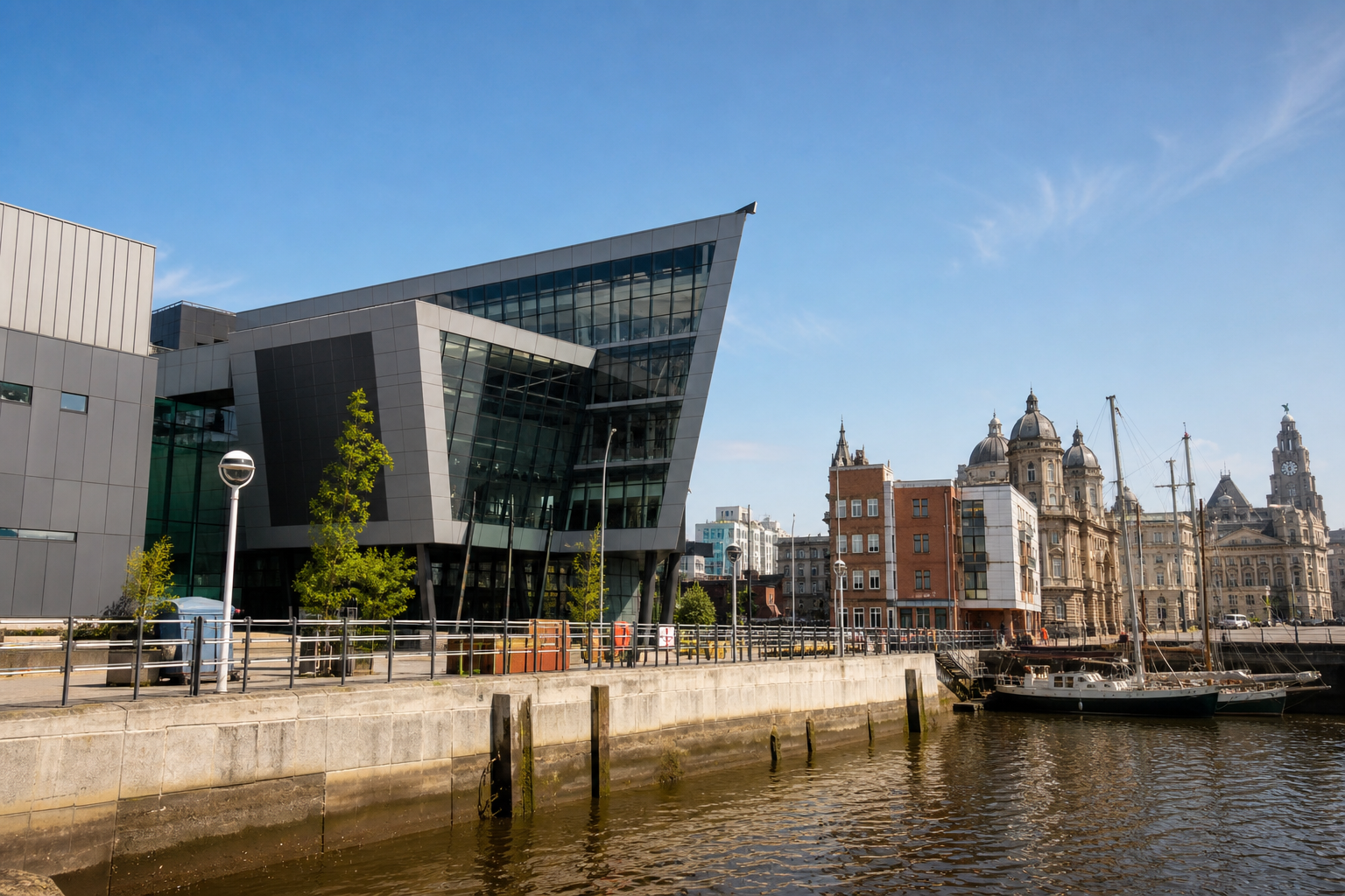 Modern and historic buildings overlooking a waterfront with a docked sailboat.