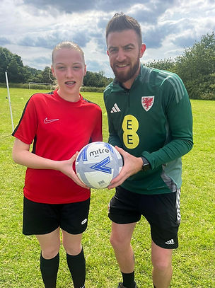 Young female footballer and football coach holding a ball
