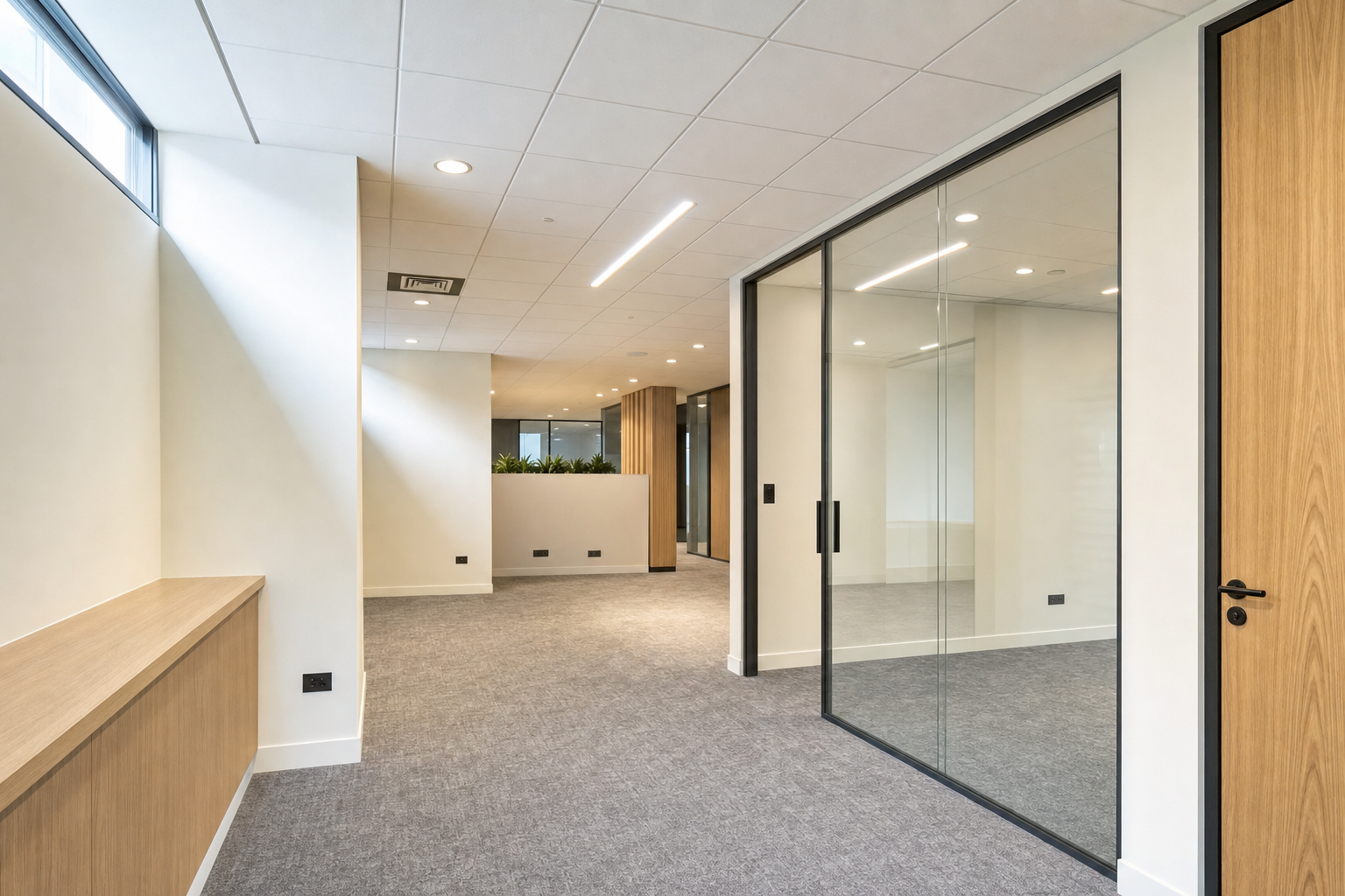 Modern office interior with glass partitions, wooden accents, and grey carpeting.