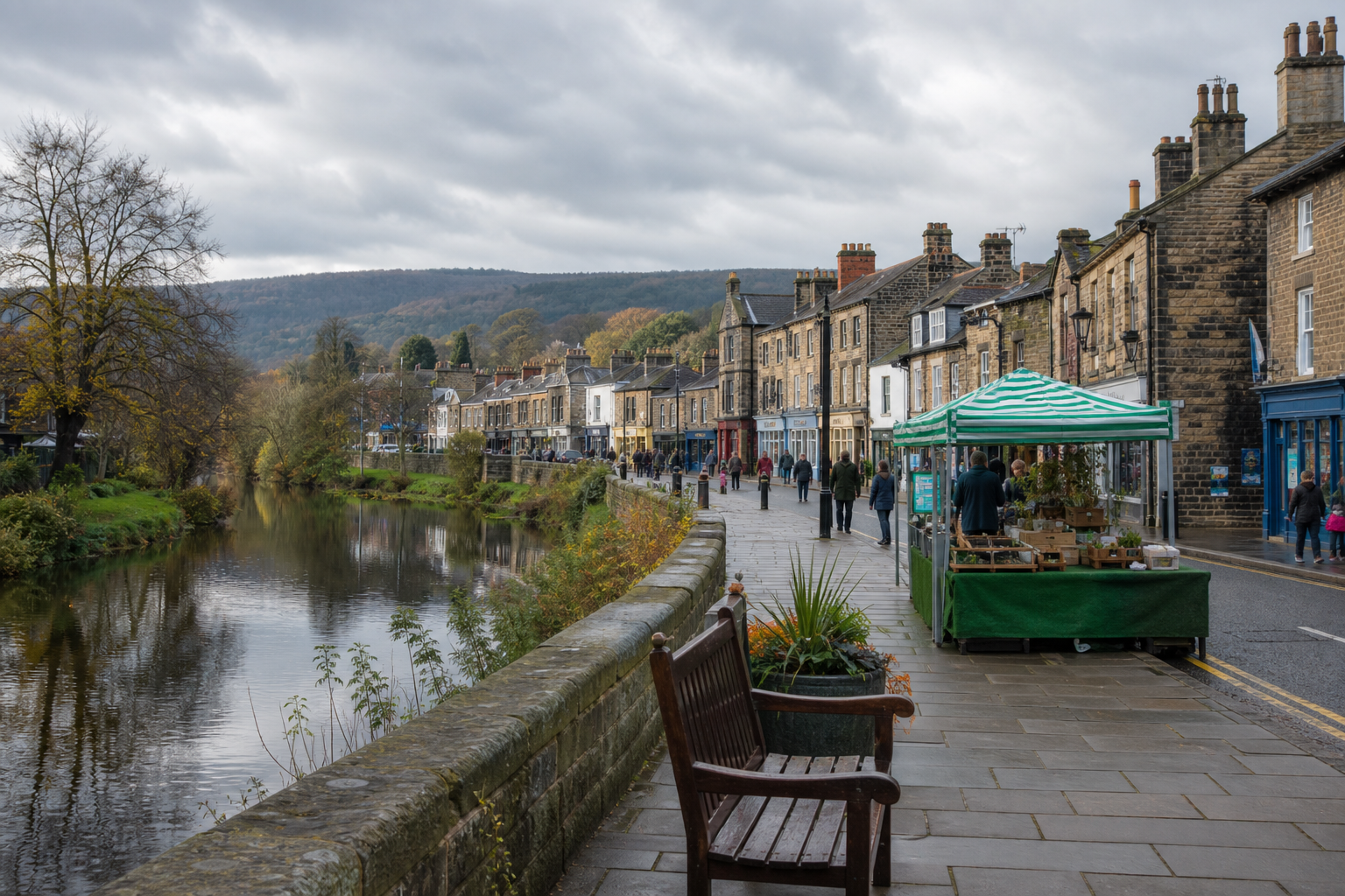 Riverside promenade lined with stone buildings and an outdoor market stall under a grey sky.