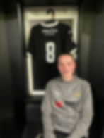 young female footballer sitting in front of football shirt