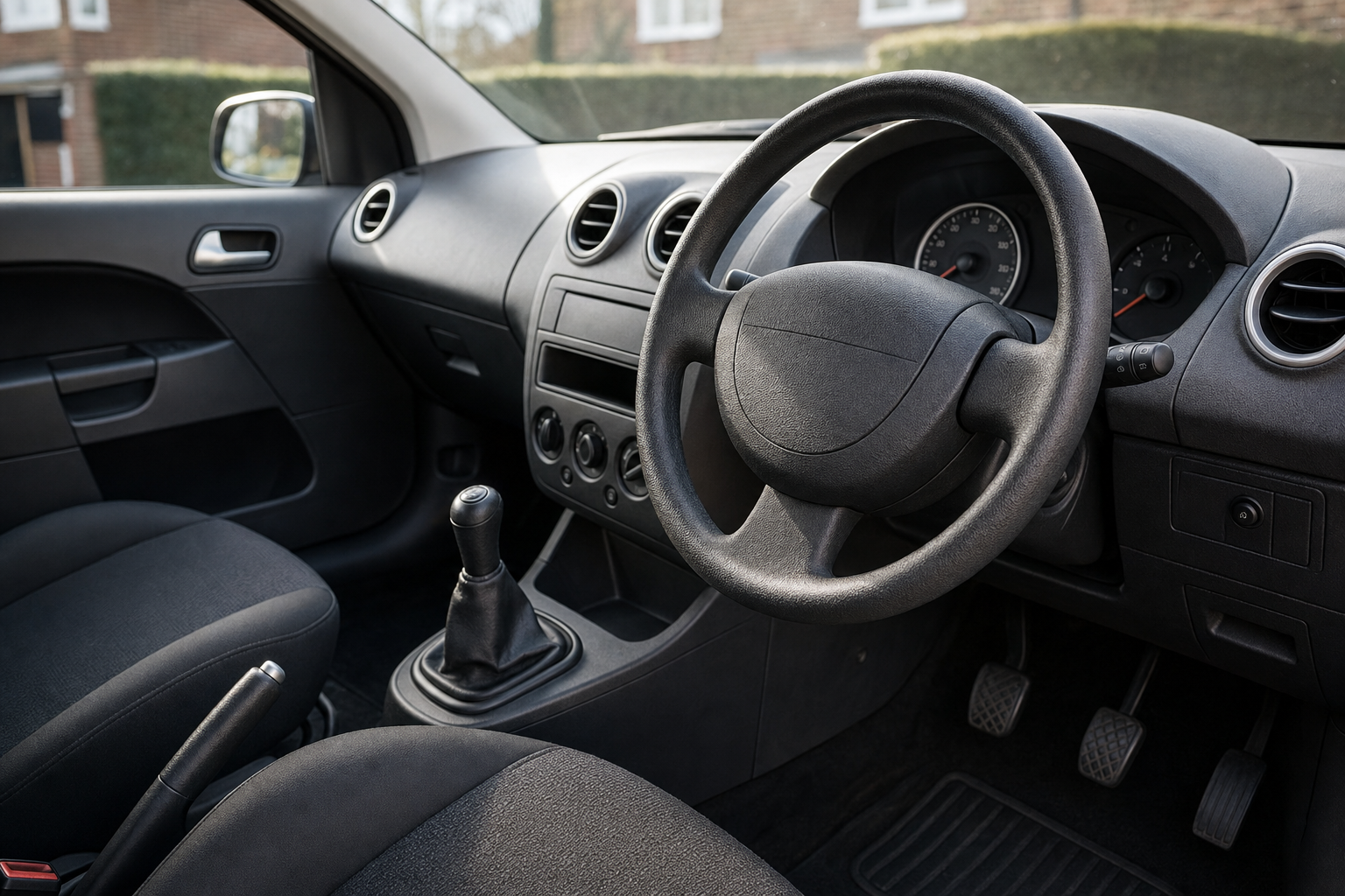 Car interior featuring a steering wheel, gear stick, and dashboard controls seen from the driver's side.