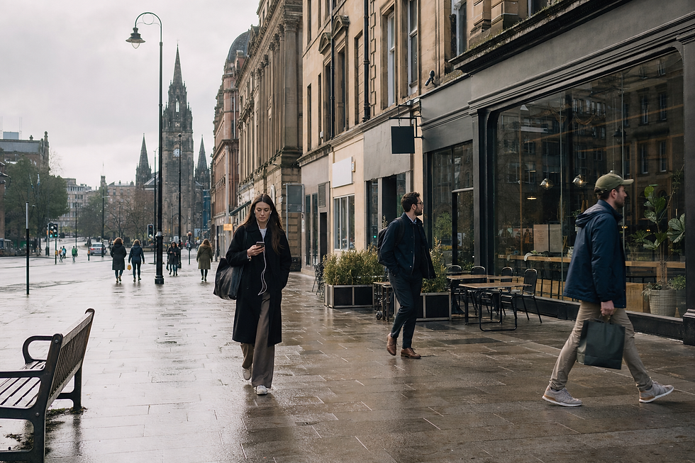People walking on a wet city street lined with historic buildings and a tall clock tower in the distance.