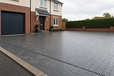 Modern brick house with a clean, spacious driveway and neatly trimmed hedges.