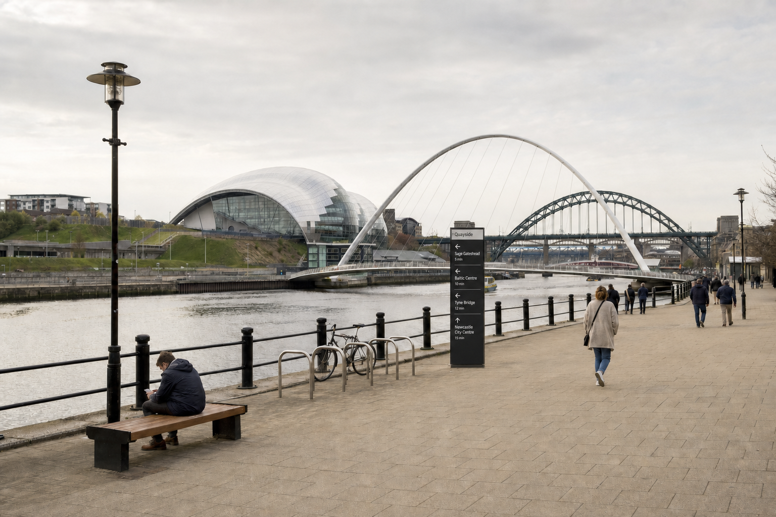 People walking along the Newcastle Quayside with visible bridges and the Sage Gateshead in the background.