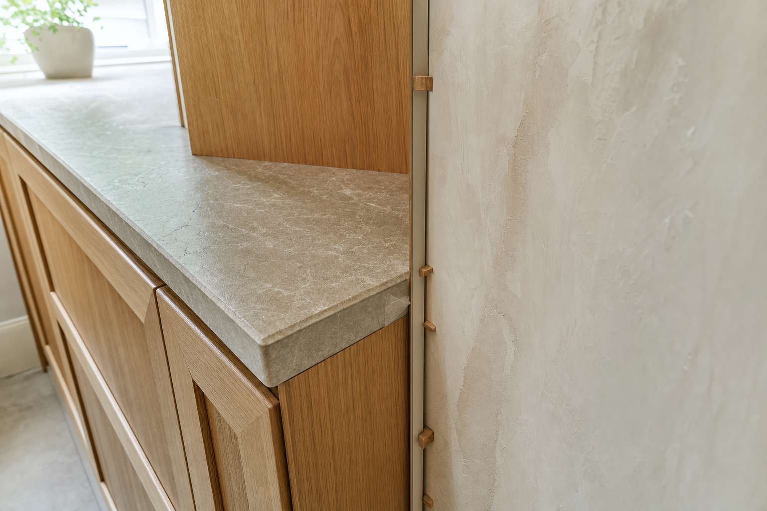 Wooden kitchen cabinets with a marble-effect countertop beside a textured wall.