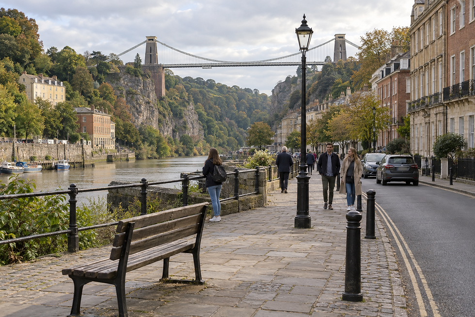People strolling along a riverside path with a view of the Clifton Suspension Bridge in the background.