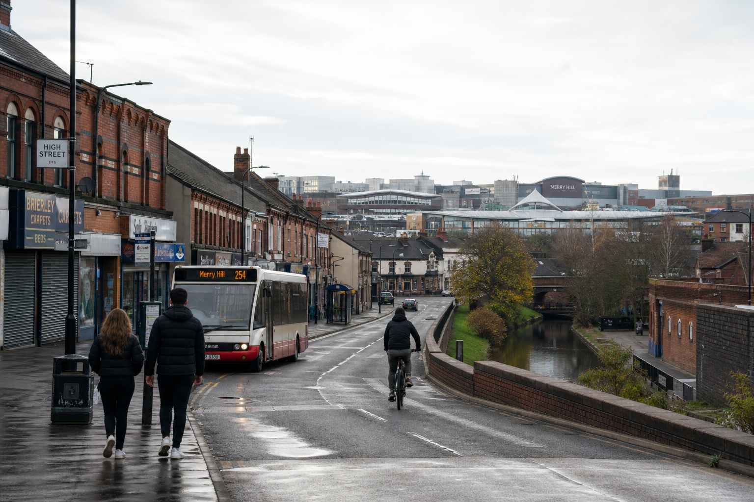 Two people walking past a bus on a wet high street, with a cyclist and buildings in the background.