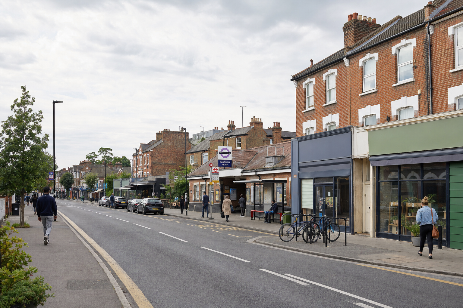 Street view of Chiswick station with people walking and cycling and cars parked along the brick buildings.