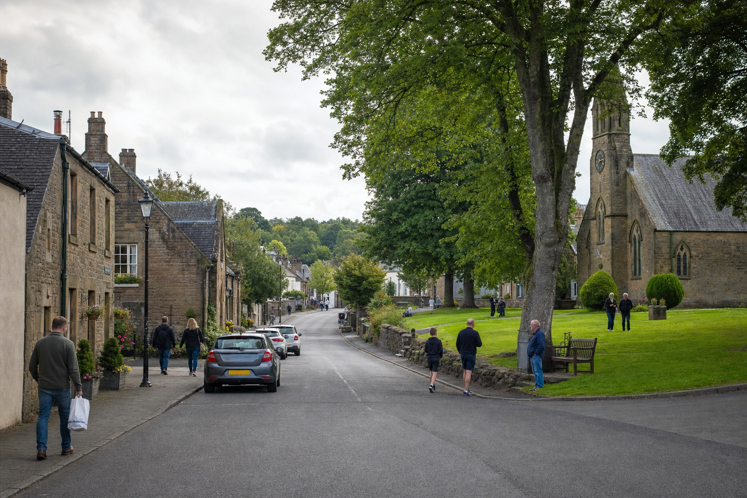 A quaint village street with people walking by stone houses and a church surrounded by green lawns and trees.