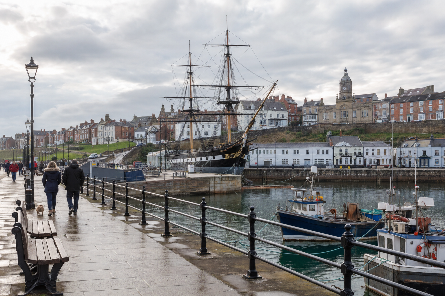 Historic harbour with a moored tall ship, surrounded by classic buildings, as pedestrians walk along a wet stone promenade.