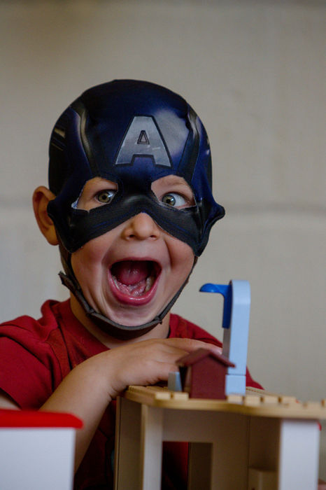 A child laughing in a superhero mask