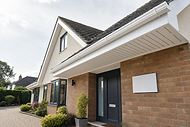 Modern house exterior with brick facade, black door, and landscaped garden on a clear day.
