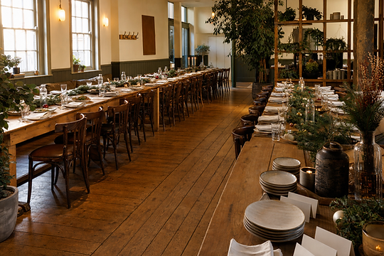 A decorated holiday dining table featuring a spread of Thai food, wine glasses, lit candles, and festive holiday decorations for group celebrations