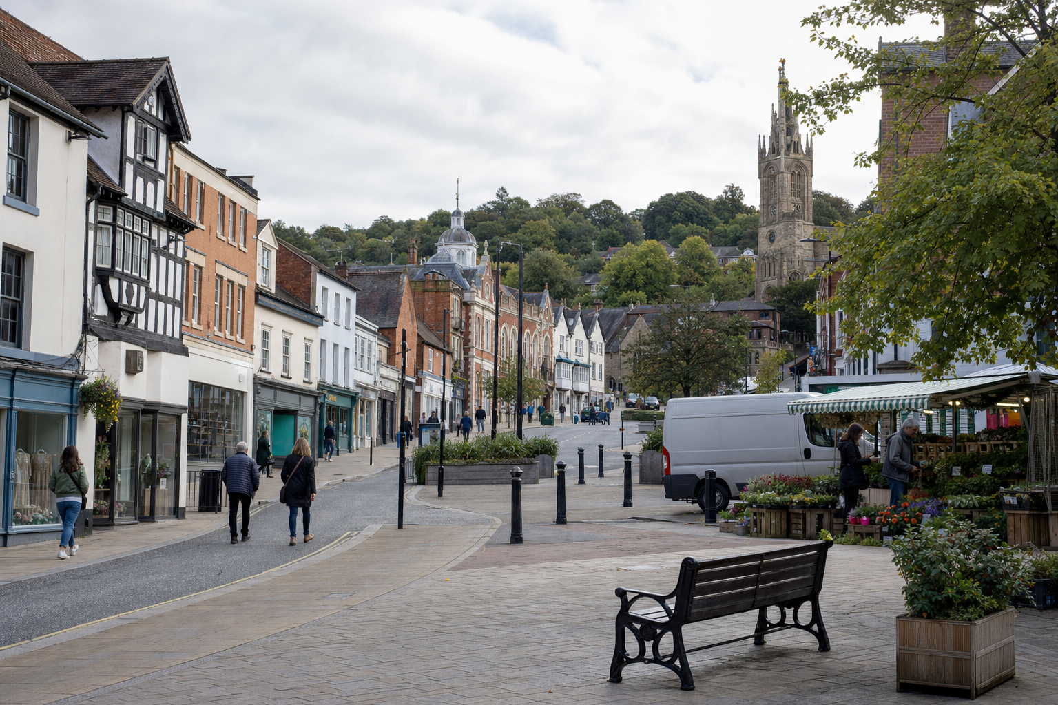A charming British high street with historic buildings, a church tower, and a bustling outdoor flower market.