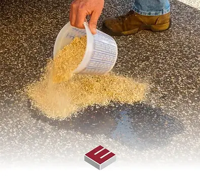 Worker throwing dry stone dust from a container onto a fresh tarmac pavement joint line