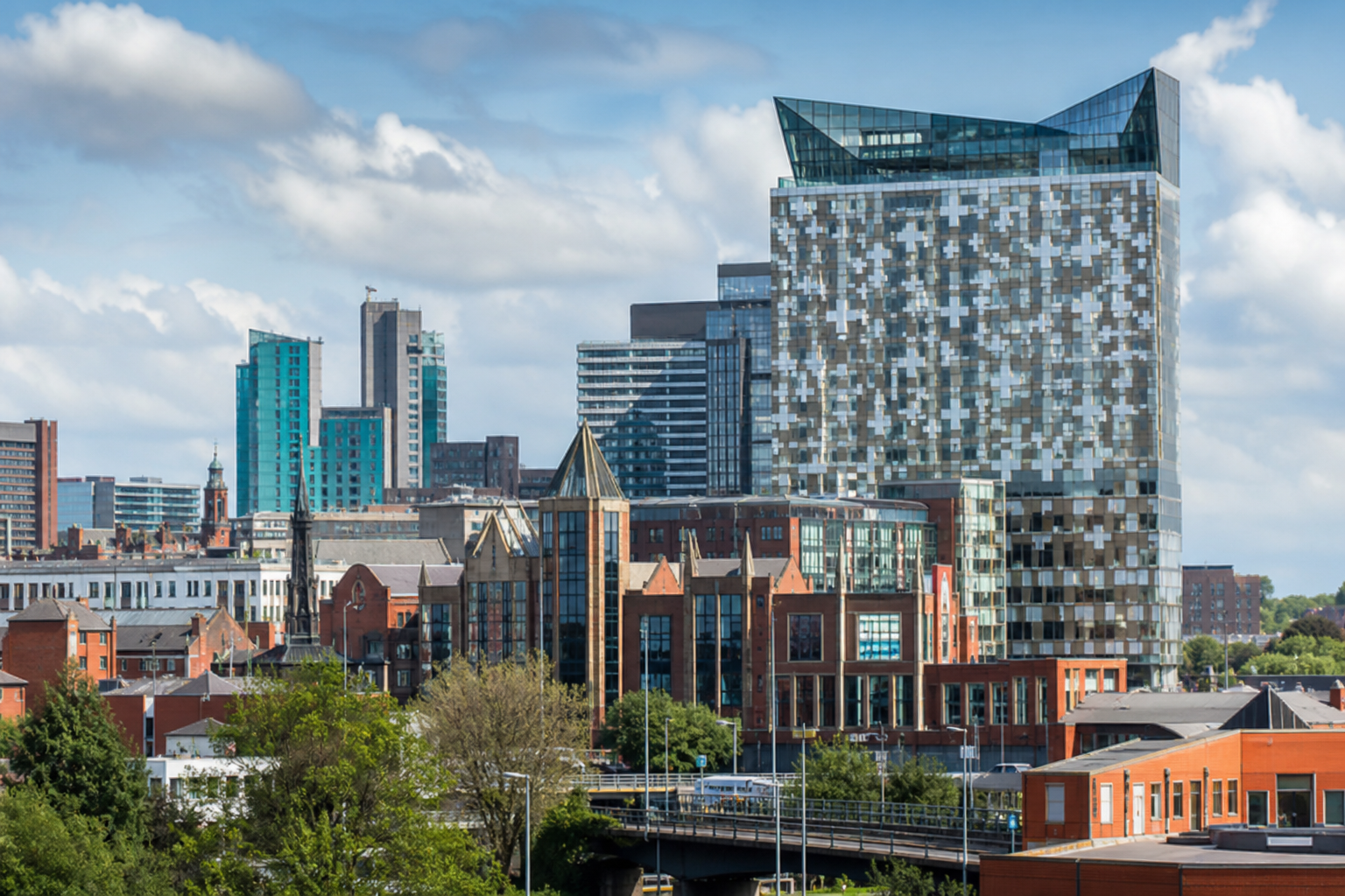 Modern cityscape featuring a tall, uniquely patterned building against a blue sky.